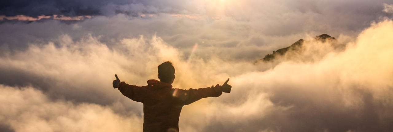 Man holds his thumbs up in front of clouds. Certified in SuccessFactors Employee Central