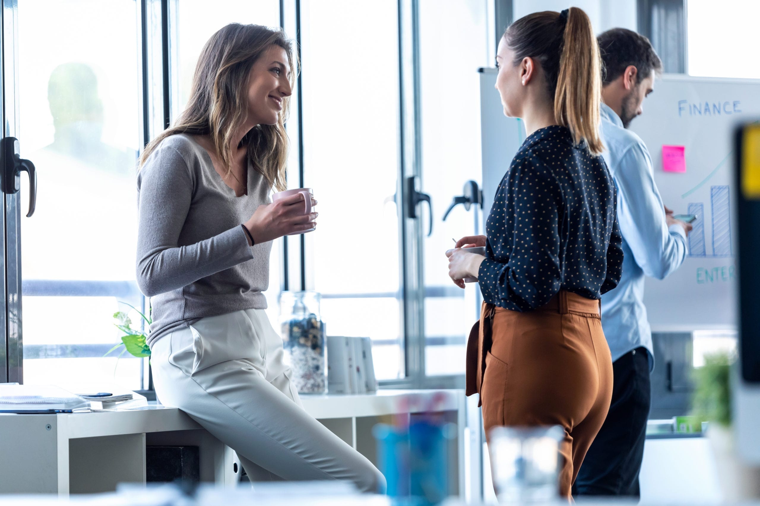 Two business young woman drinking coffee while taking a break on